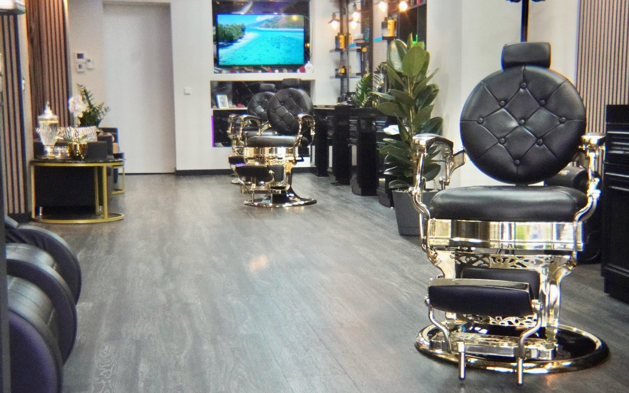 De zaak van Top Tier Barbershop: zwart-gouden barbierstoelen langs de spiegels, rechts vooraan een stoel met gouden onderstel